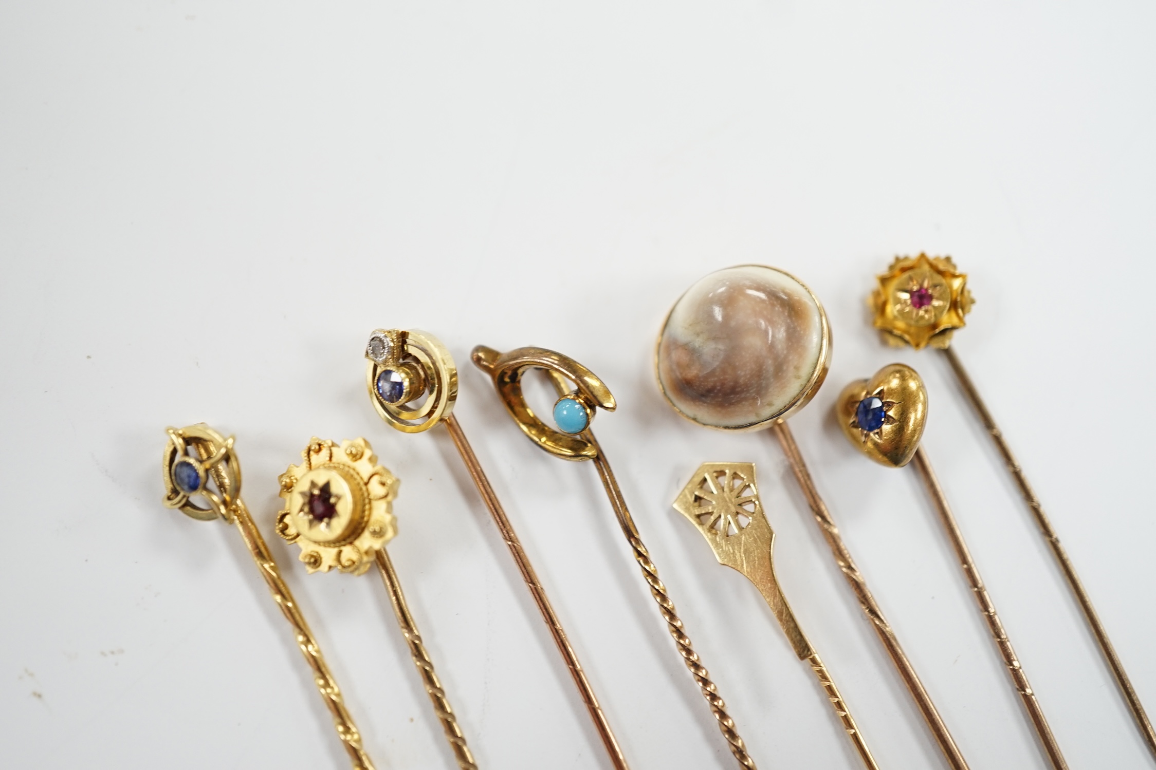 Eight assorted early 20th century and later yellow metal and gem set stick pins, including six 15ct, one 585 and one unmarked yellow metal, largest set with sapphire, 59mm, gross weight 11 grams.